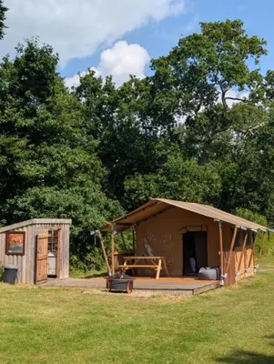 a large wooden hut in a grass field at Cefn Crib Safari Tent in Machynlleth