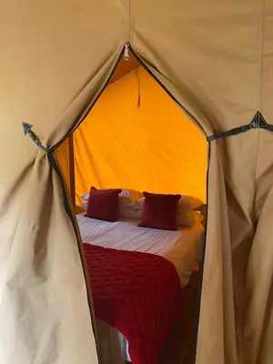 a bed in a tent with a red blanket at Cefn Crib Safari Tent in Machynlleth