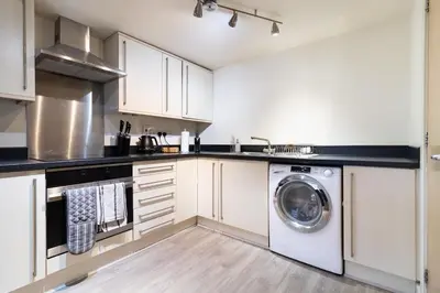 a kitchen with white cabinets and a washing machine at 2 bedroom apartment - Shrewsbury town centre in Shrewsbury