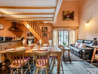 a kitchen and living room with a wooden table and chairs at Y Cartws in Llanybydder