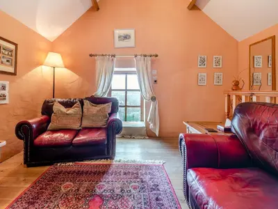 a living room with leather furniture and a window at Y Cartws in Llanybydder