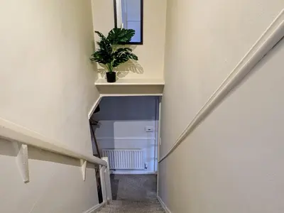 a hallway with a staircase with a plant on a shelf at Theatre Severn Town House, Parking & Quarry Views in Shrewsbury
