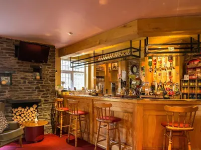 a bar in a pub with stools and a fireplace at The Castle Hotel in Talgarth