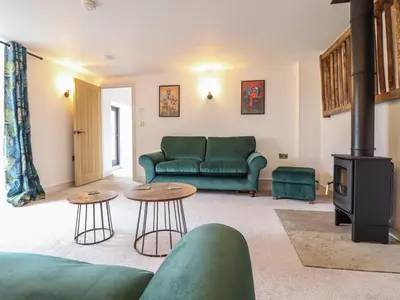 a living room with a green couch and a stove at Sally's Barn in Oswestry