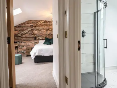 a glass shower in a bedroom with a bed at Sally's Barn in Oswestry