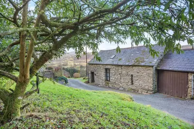 a stone house on a hill with a tree at 1 Bed in Llandderfel oc-t30475 in Llandderfel