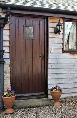 a wooden garage with two flower pots in front of it at Herdsman's Hideaway in Leominster