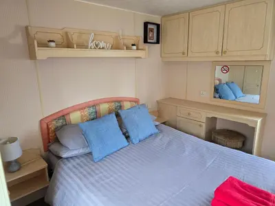 a bedroom with a bed with blue pillows at Homely 2 Bedrommed Mobile Home E1 in Aberystwyth
