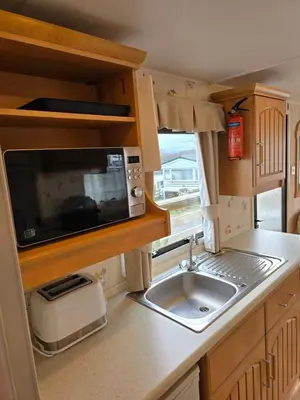 a kitchen with a sink and a microwave at Homely 2 Bedrommed Mobile Home E1 in Aberystwyth