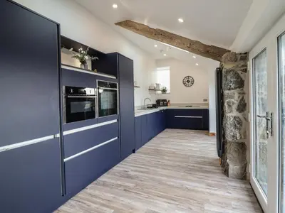 a kitchen with blue cabinets and wood floors at Gaerau Bach in Llanbedr