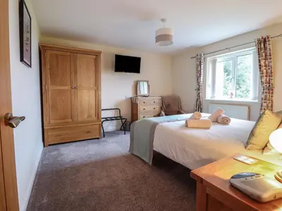 a bedroom with a bed and a dresser and a television at Ysgubor Newydd Parc Isaf in Dyffryn