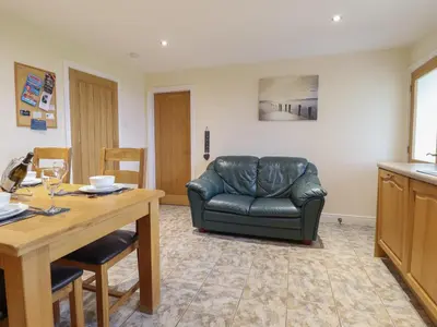 a living room with a leather couch and a table at Ysgubor Newydd Parc Isaf in Dyffryn