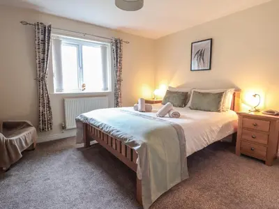 a bedroom with a large bed and a window at Ysgubor Newydd Parc Isaf in Dyffryn