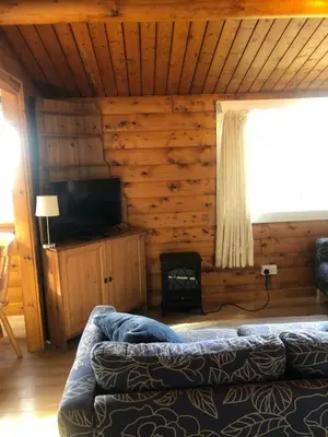 a room with a couch and a television in a cabin at Misty Mountain Log Cabin - Trawsfynydd in Trawsfynydd