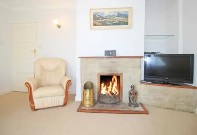a living room with a fireplace and a tv at Artist's Cottage in Penrhyndeudreath