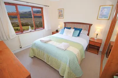 a bedroom with a large bed and a window at Artist's Cottage in Penrhyndeudreath