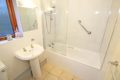 a white bathroom with a sink and a shower at Artist's Cottage in Penrhyndeudreath