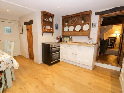 a kitchen with white cabinets and a stove top oven at Glandwr Cottage in Llanbedr