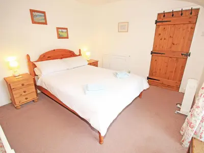 a bedroom with a large bed with a wooden headboard at The Farmhouse in Llanbedr