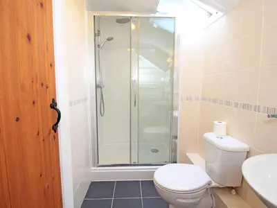 a bathroom with a shower and a toilet and a sink at The Farmhouse in Llanbedr