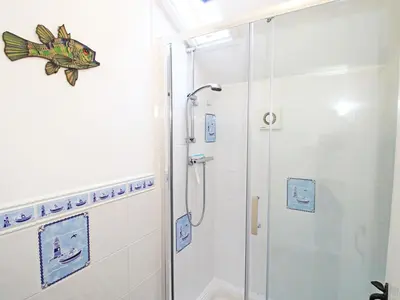 a bathroom with a shower with a fish on the wall at The Farmhouse in Llanbedr