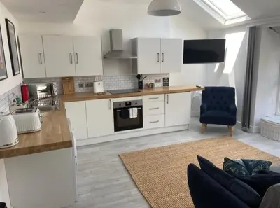 a kitchen with white cabinets and a couch in a room at Sandpiper Apartment in Barmouth