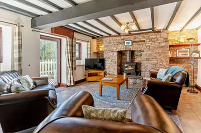 a living room with leather furniture and a stone fireplace at 3 Bed in Pentre Bach oc-t30863 in Pentre-bâch