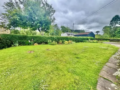 a yard with a green lawn with flowers in it at 3 Bed in Pentre Bach oc-t30863 in Pentre-bâch