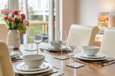 a table with plates and glasses and a vase with flowers at 2 Bed in Gilfachrheda oc-b30905 in Llanina