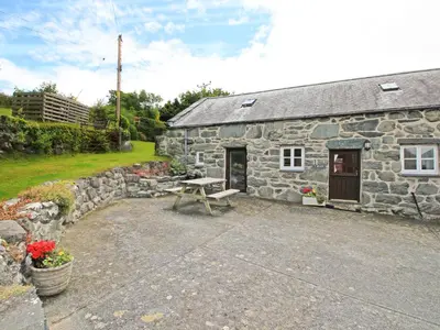 a stone cottage with a picnic table in front of it at Y Beudy The Old Byre in Llanbedr