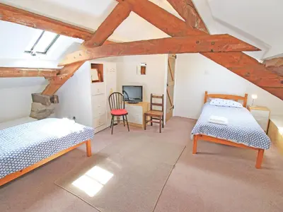 a attic bedroom with two beds and a desk at Y Beudy The Old Byre in Llanbedr