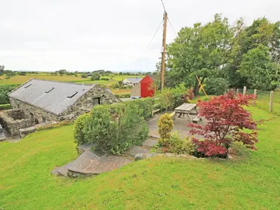 a garden with a picnic table and a barn at Y Beudy The Old Byre in Llanbedr