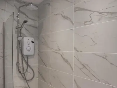 a bathroom with a shower with marble tiles at Tynffordd Fawr in Penrhyndeudreath