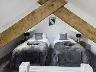 two twin beds in a attic room with wooden beams at Tynffordd Fawr in Penrhyndeudreath