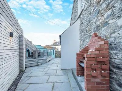 a brick wall next to a building with a patio at Bettys Cottage in New Quay