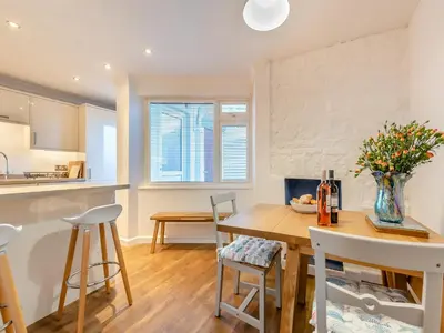 a kitchen and dining room with a wooden table and chairs at Bettys Cottage in New Quay
