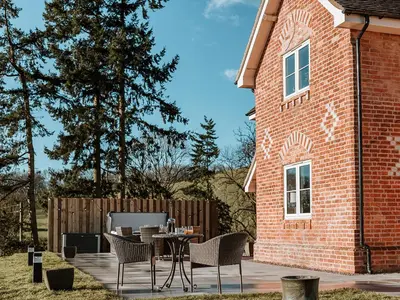 a patio with a table and chairs next to a brick building at Copper Beech Cottage in Welshpool