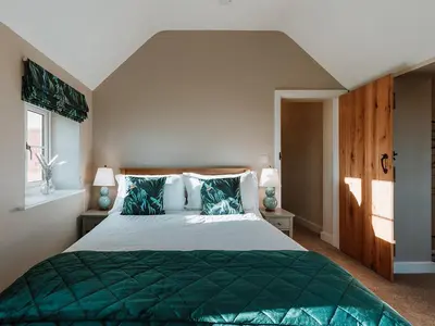 a bedroom with a large bed with green sheets and pillows at Copper Beech Cottage in Welshpool