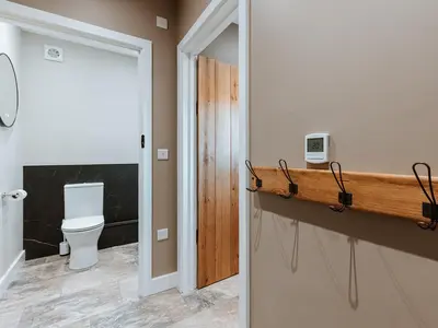 a bathroom with a toilet and a wooden shelf at Copper Beech Cottage in Welshpool