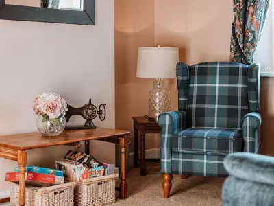 a living room with a chair and a table at Copper Beech Cottage in Welshpool