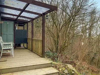 a wooden deck with a pergola and a chair on it at The Cabin In The Woods - Uk49023 in Pencarreg