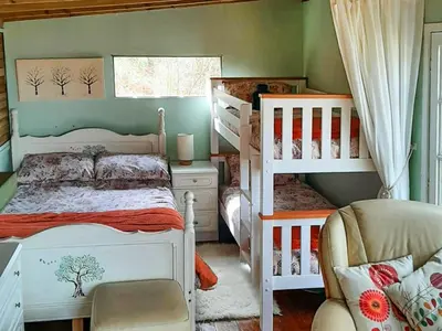 a bedroom with two bunk beds and a chair at The Cabin In The Woods - Uk49023 in Pencarreg