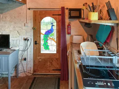 a kitchen with a door with a peacock window at Y Smithy - Uk49022 in Llanybydder