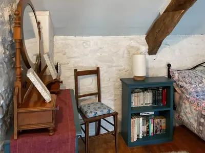 a bedroom with a chair a mirror and a book shelf at Y Smithy - Uk49022 in Llanybydder