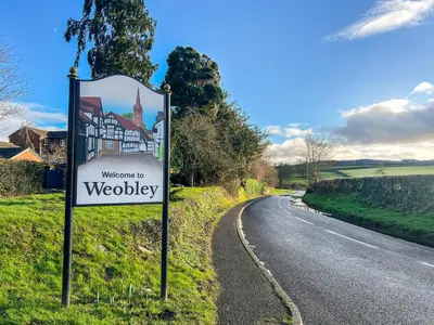 a welcome to wodbey sign next to a road at The Cottage in Weobley