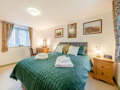 a bedroom with a green bed with two towels on it at Rhydyfran Coach House in Cribyn