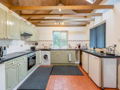 a kitchen with green cabinets and a washer and dryer at Rhydyfran Coach House in Cribyn