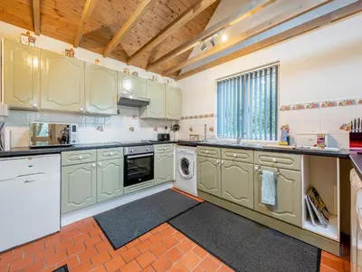 a large kitchen with white cabinets and a washer and dryer at Rhydyfran Coach House in Cribyn