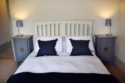 a bed with three pillows and two night stands at Awel Mor Holiday Apartment in Aberystwyth