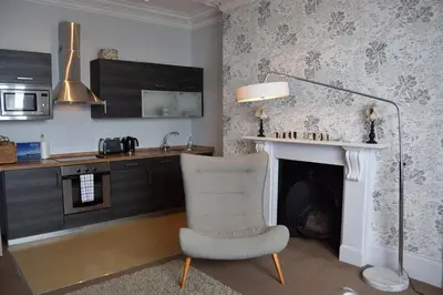 a living room with a chair and a fireplace at Awel Mor Holiday Apartment in Aberystwyth